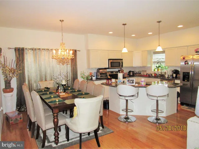 a dining room with stainless steel appliances kitchen island granite countertop a table chairs and a living room view