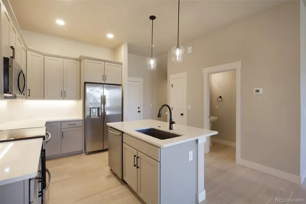 a kitchen that has a refrigerator a sink and a stove top oven with wooden floor