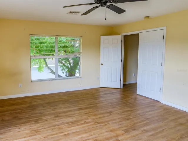 a view of an empty room with window and wooden floor