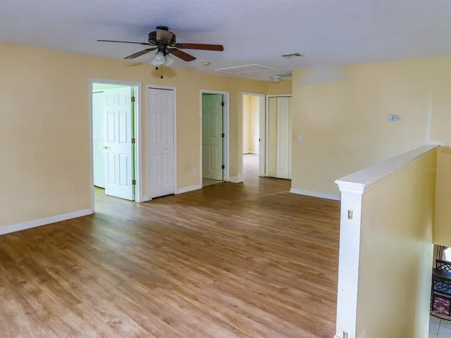 a view of a room with wooden floor and a ceiling fan