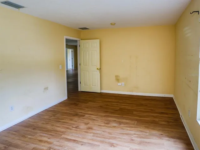 a view of an empty room with wooden floor and closet