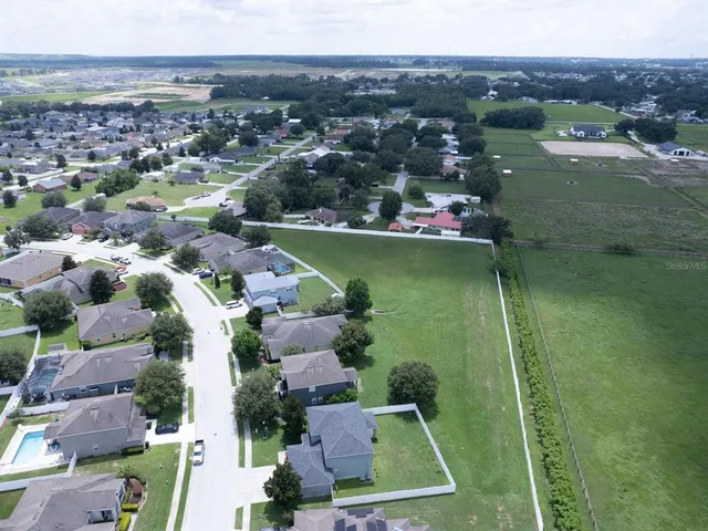 an aerial view of residential houses with outdoor space and lake view