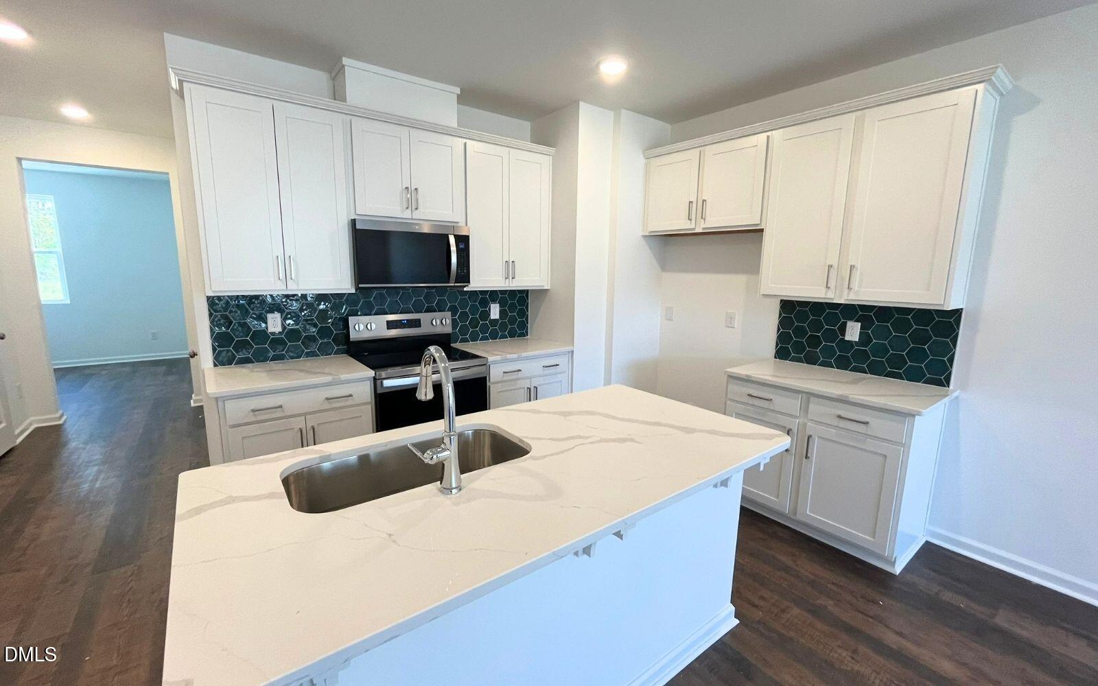 2430 Whitewing Lane Wendell, NC 27591 - Photo 5 of 31 a kitchen with kitchen island a stove a sink a microwave and wooden cabinets