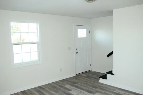 an empty room with wooden floor cabinet and windows