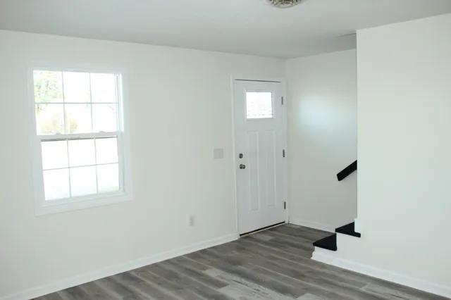 an empty room with wooden floor cabinet and windows