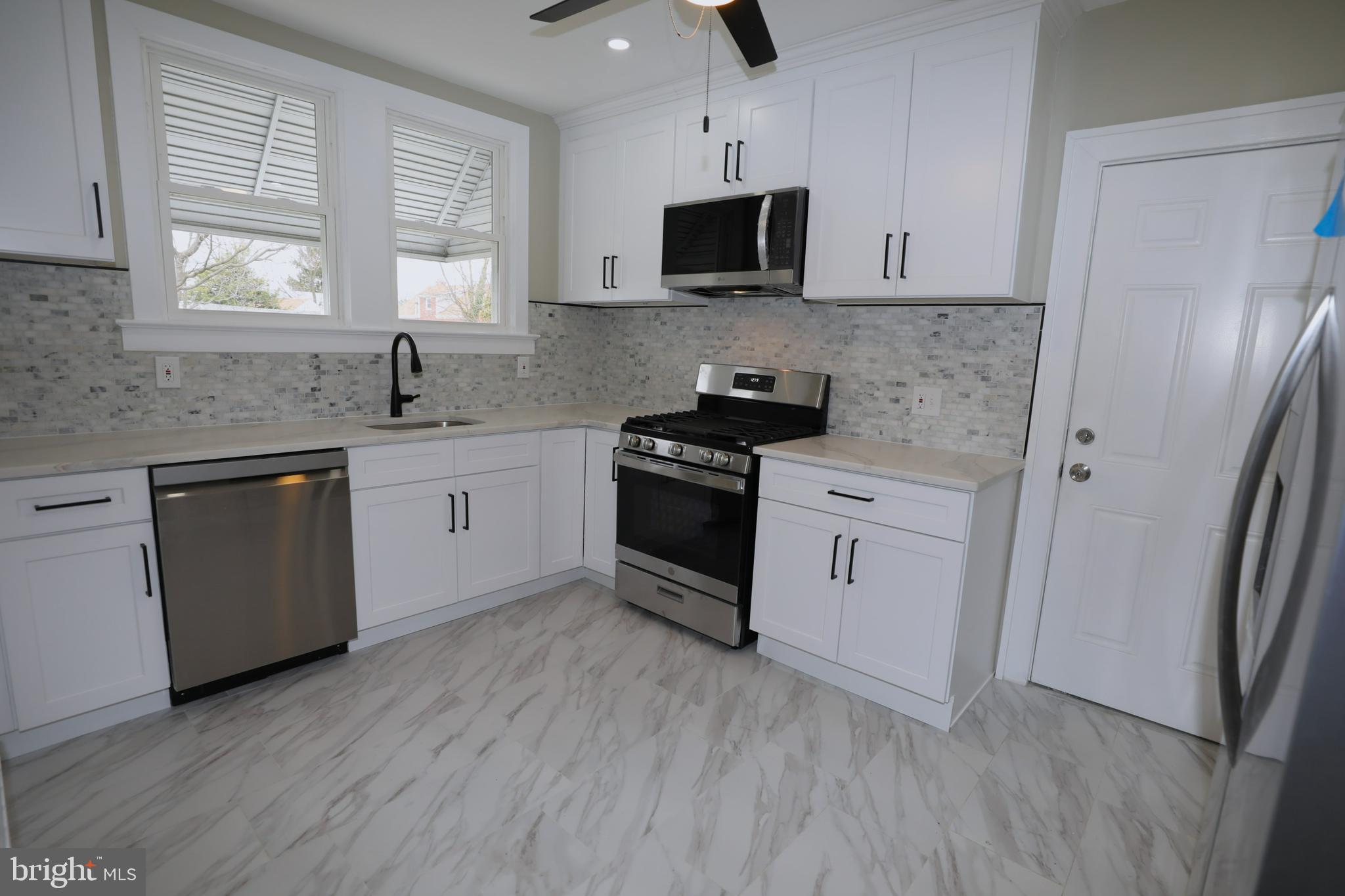 36 Emanuel Street Hamilton, NJ 08610 - Photo 6 of 26 a kitchen with stainless steel appliances white cabinets a sink a stove a microwave and wooden floors