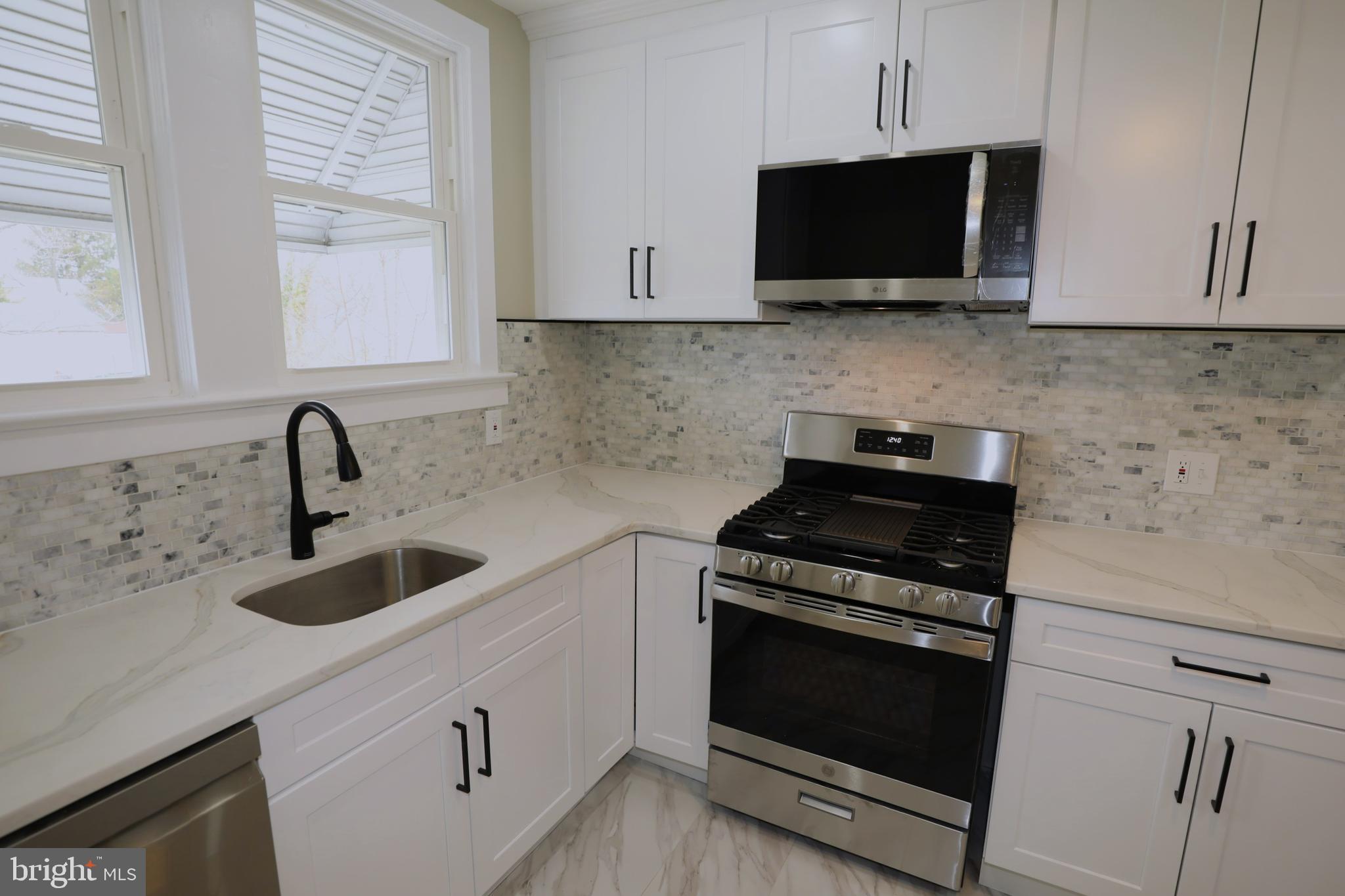 36 Emanuel Street Hamilton, NJ 08610 - Photo 8 of 26 a kitchen with stainless steel appliances a stove a microwave a sink and cabinets