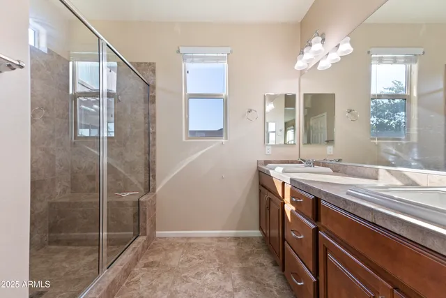 a bathroom with a granite countertop sink a large mirror and a shower