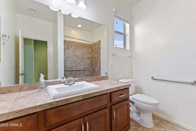 a bathroom with a granite countertop toilet sink and mirror