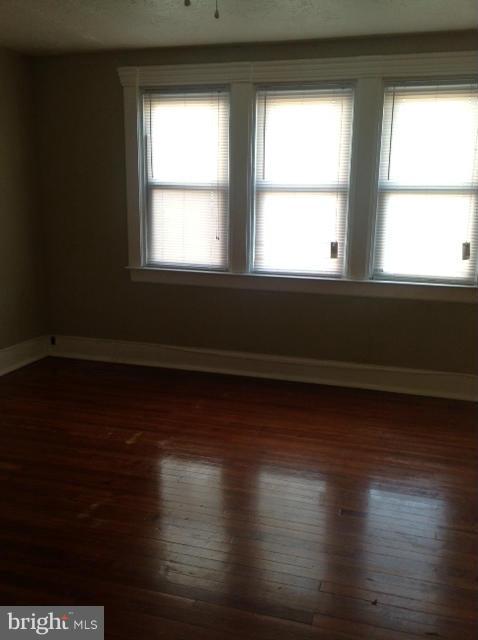 6823 Dunhill Road Baltimore, MD 21222 - Photo 8 of 13 a view of empty room with wooden floor and windows