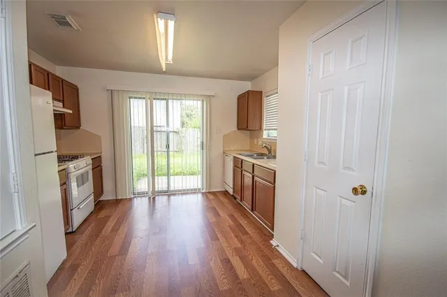 a view of a kitchen with a sink refrigerator and wooden floor