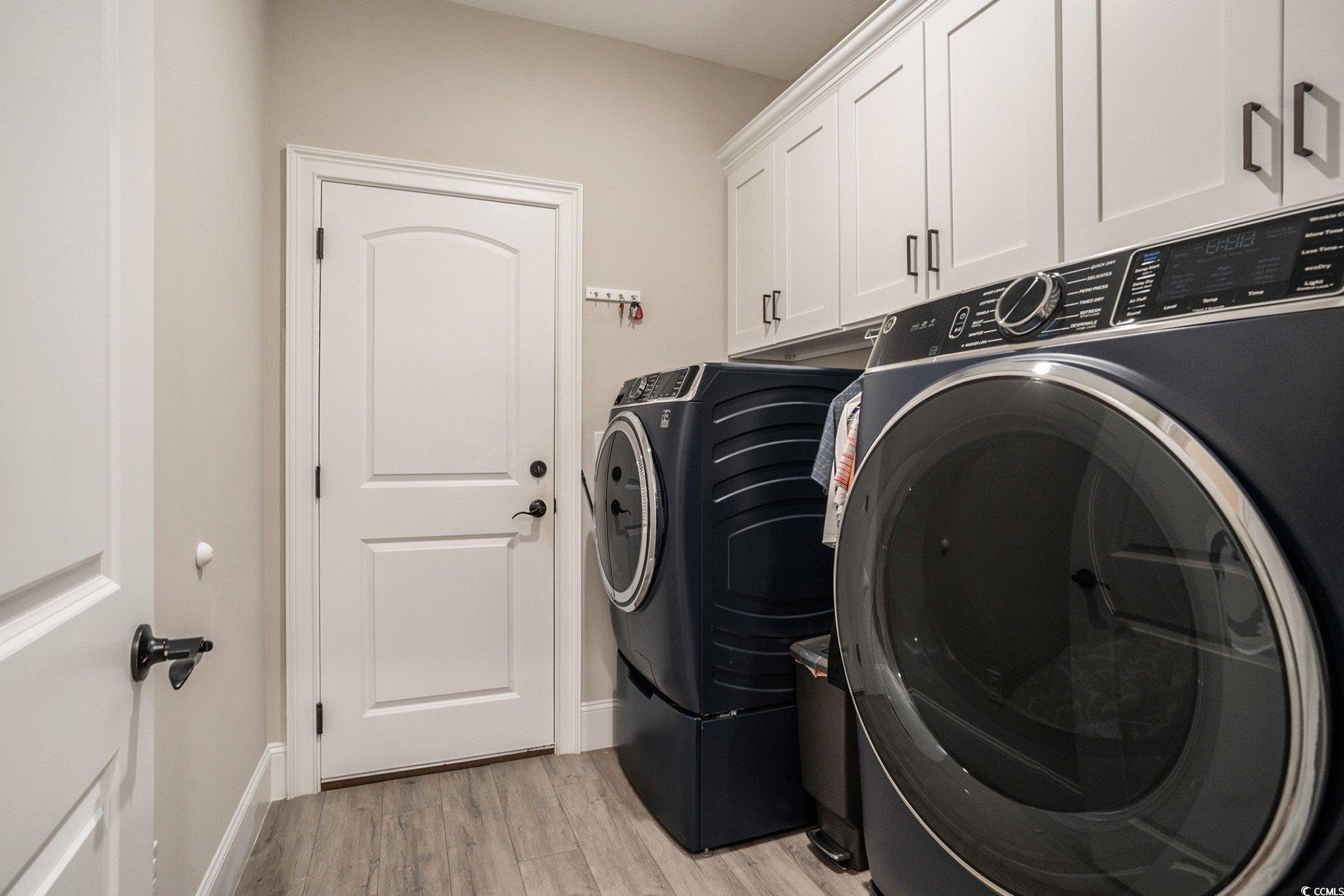 1009 Dowitcher Drive Conway, SC 29526 - Photo 28 of 40 Laundry room featuring light wood-style flooring, washing machine and dryer, and cabinet space