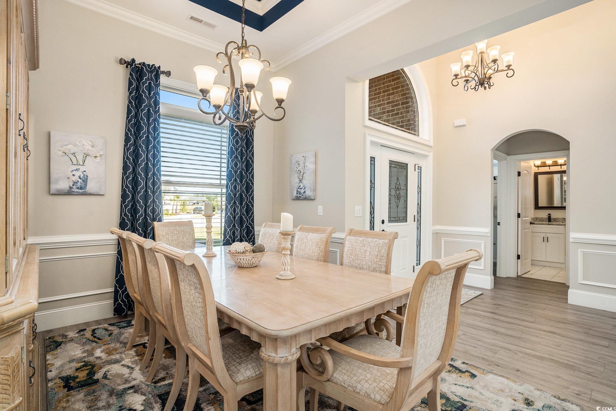 1009 Dowitcher Drive Conway, SC 29526 - Photo 5 of 40 Dining space featuring wainscoting, a decorative wall, crown molding, a chandelier, and light wood-type flooring