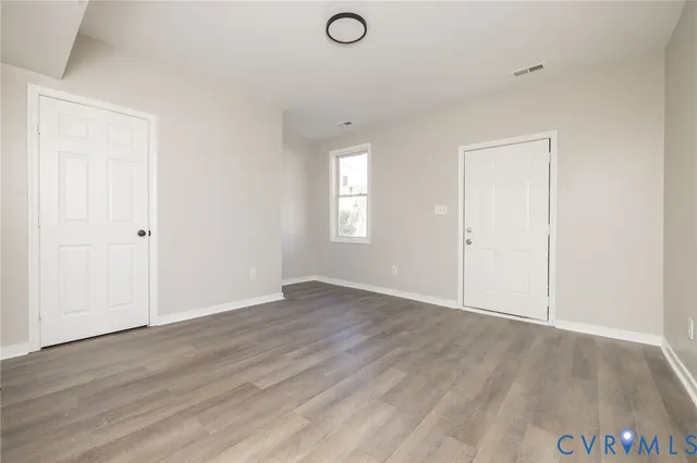 an empty room with wooden floor and windows