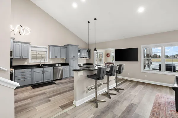 a kitchen with stainless steel appliances kitchen island granite countertop a stove top oven a sink a counter space and cabinets