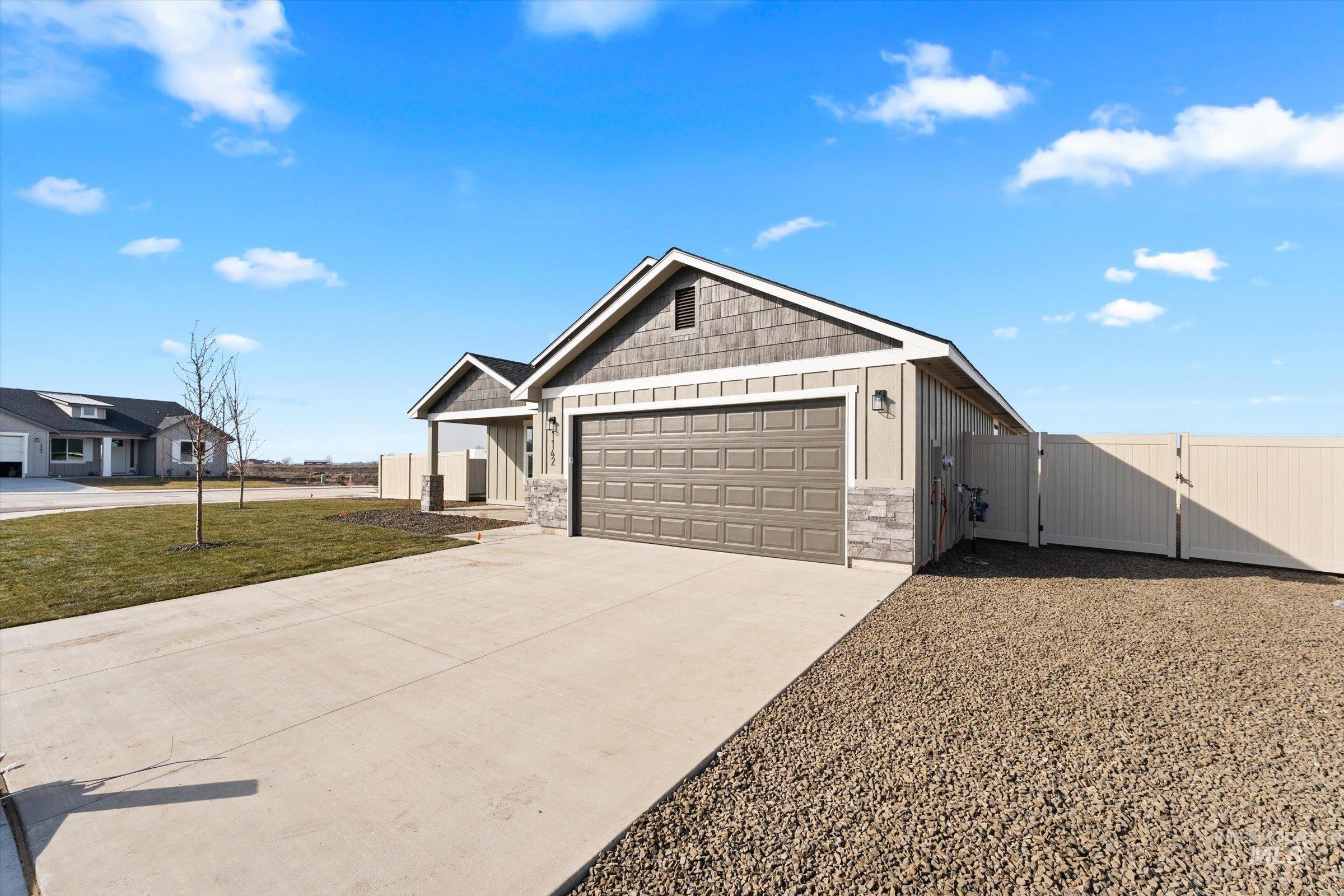 1142 Velvet Loop Wilder, ID 83676 - Photo 3 of 27 View of front of house with a gate, driveway, board and batten siding, a garage, and stone siding