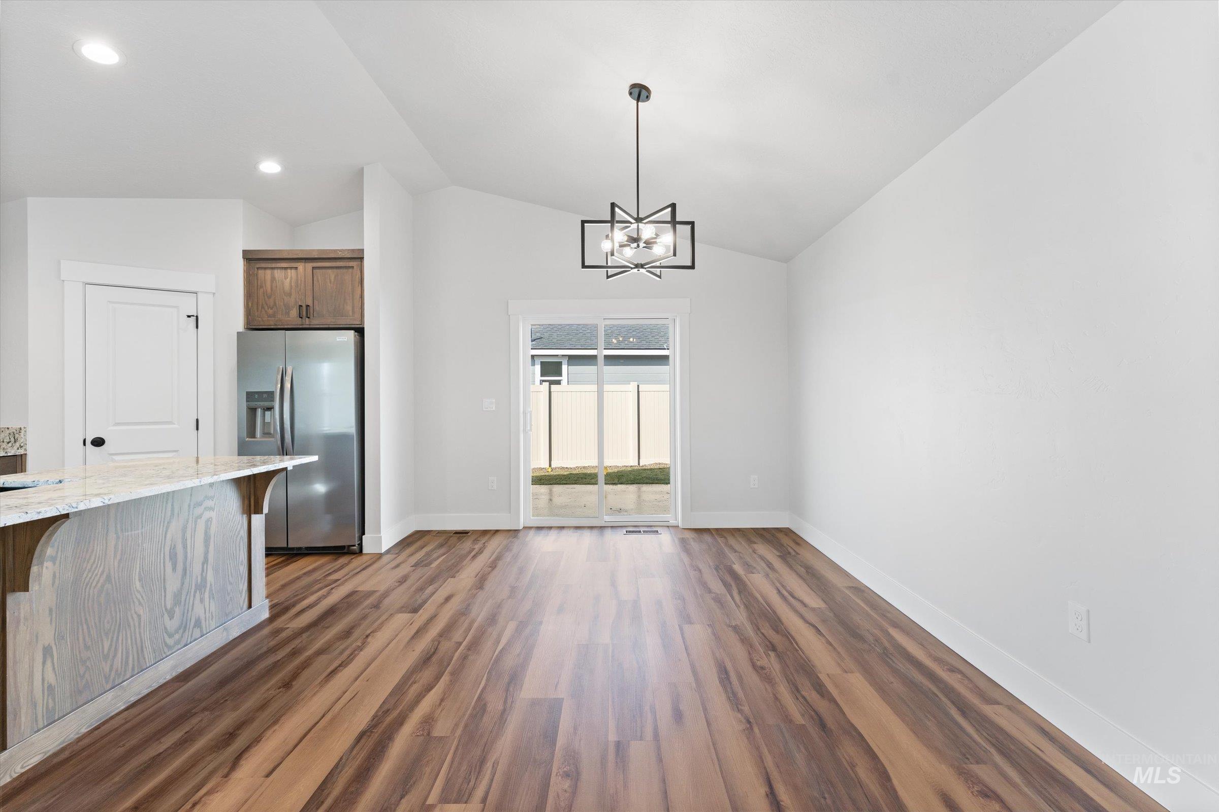 1142 Velvet Loop Wilder, ID 83676 - Photo 6 of 27 Unfurnished dining area with suspended lighting, dark wood-style floors, and lofted ceiling