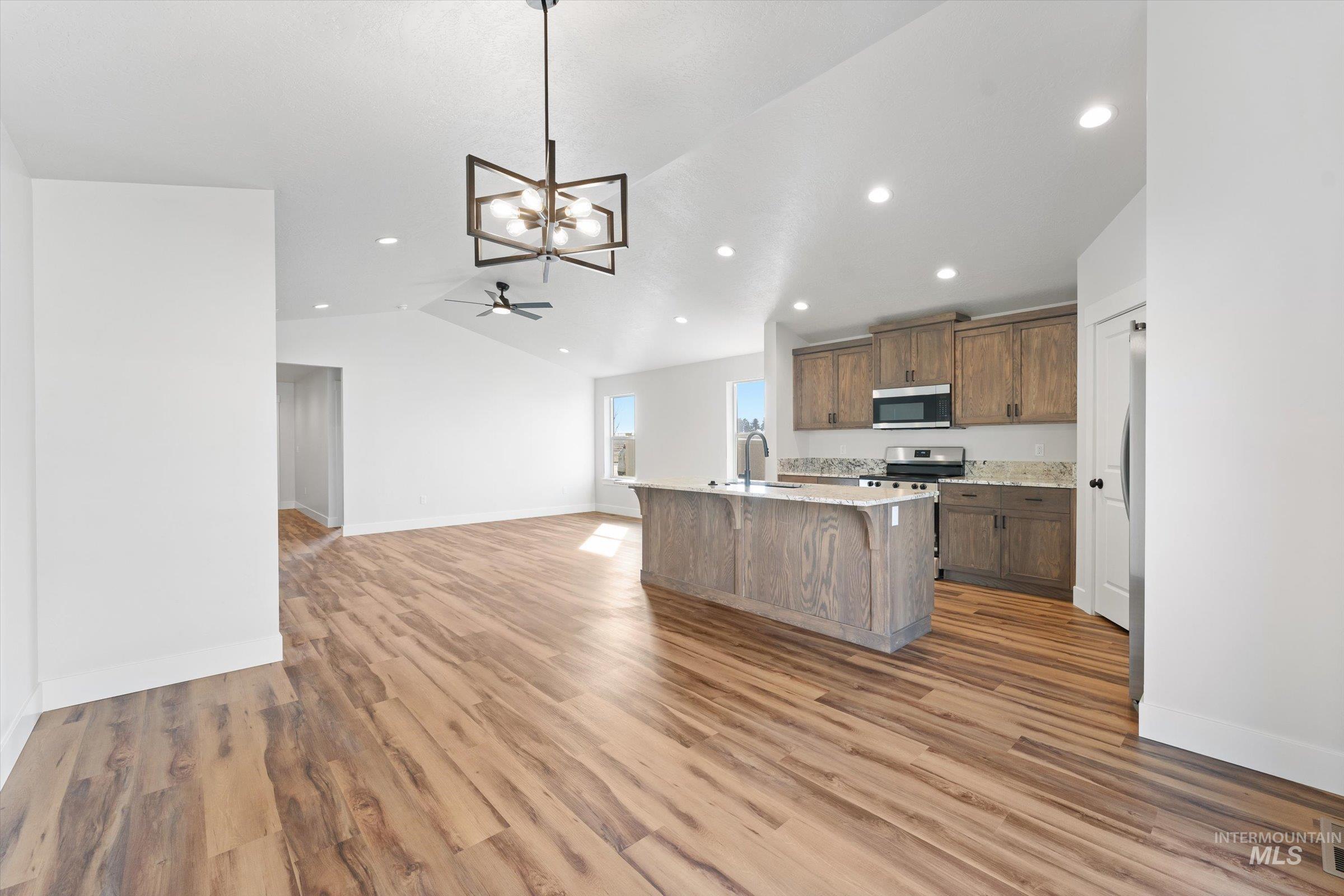 1142 Velvet Loop Wilder, ID 83676 - Photo 26 of 27 Kitchen featuring open floor plan, suspended lighting, lofted ceiling, an island with sink, and light wood finished floors