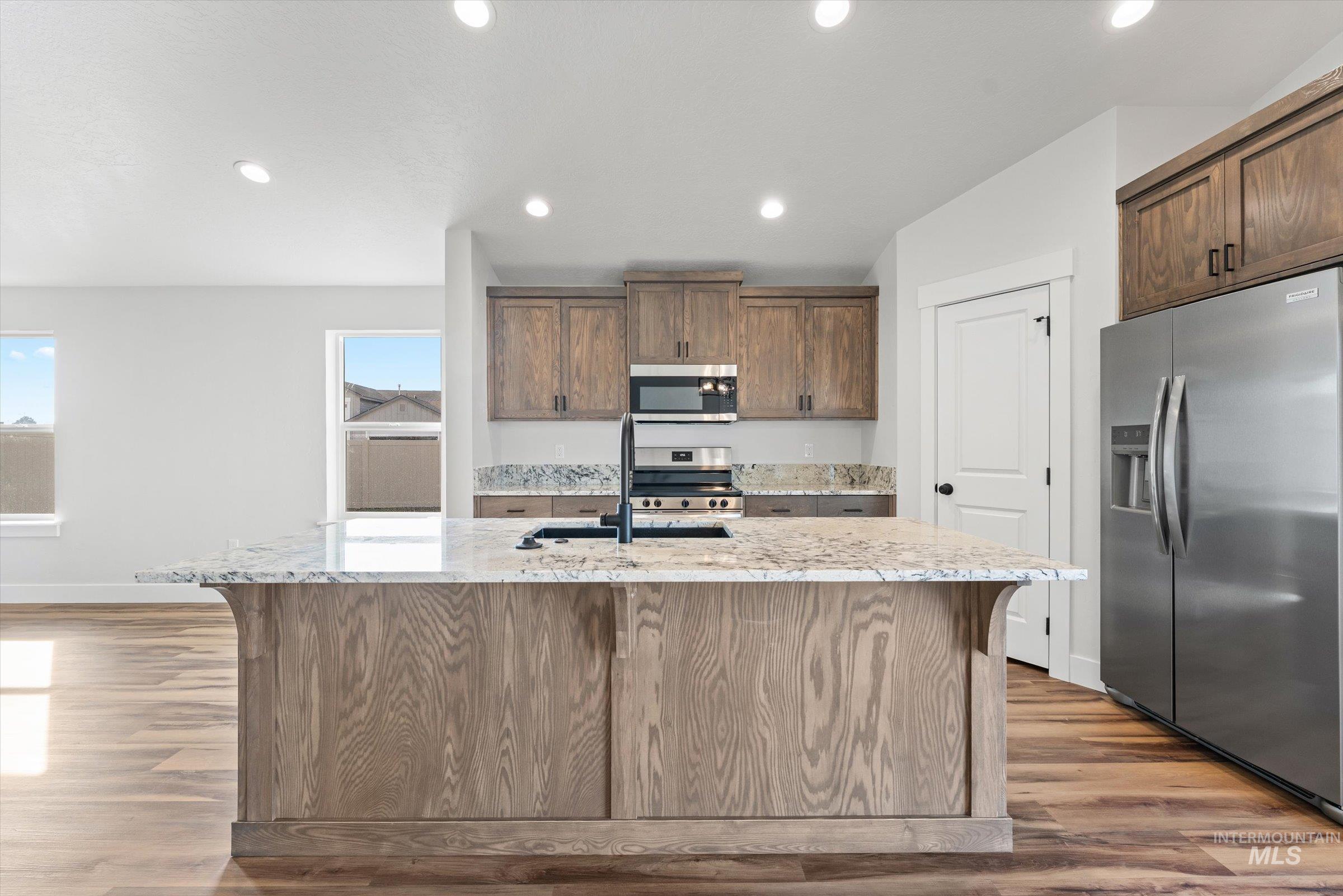 1142 Velvet Loop Wilder, ID 83676 - Photo 7 of 27 Kitchen featuring light stone countertops, stainless steel appliances, light wood-style floors, a kitchen island with sink, and recessed lighting