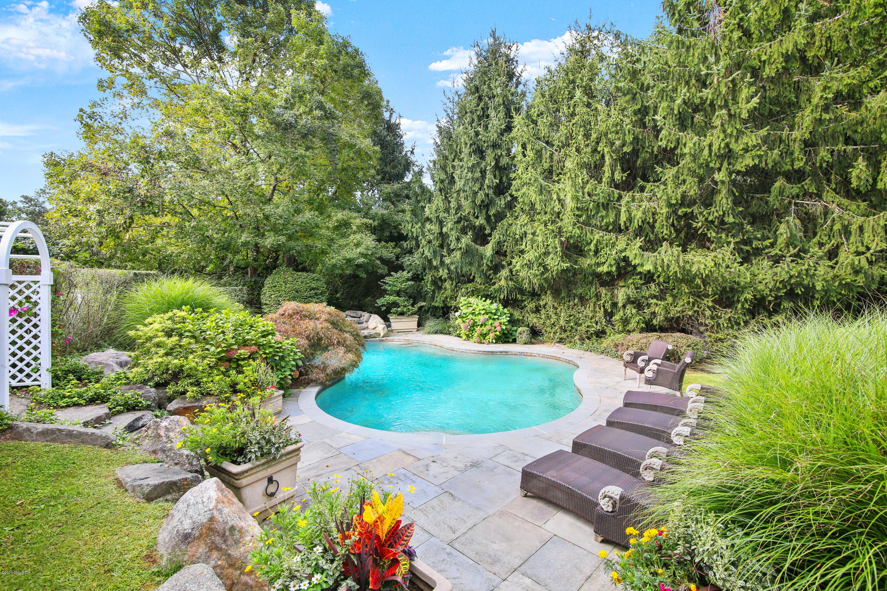 82 Round Hill Road Greenwich, CT 06831 - Photo 2 of 19 a view of a garden with a swimming pool and lawn chairs