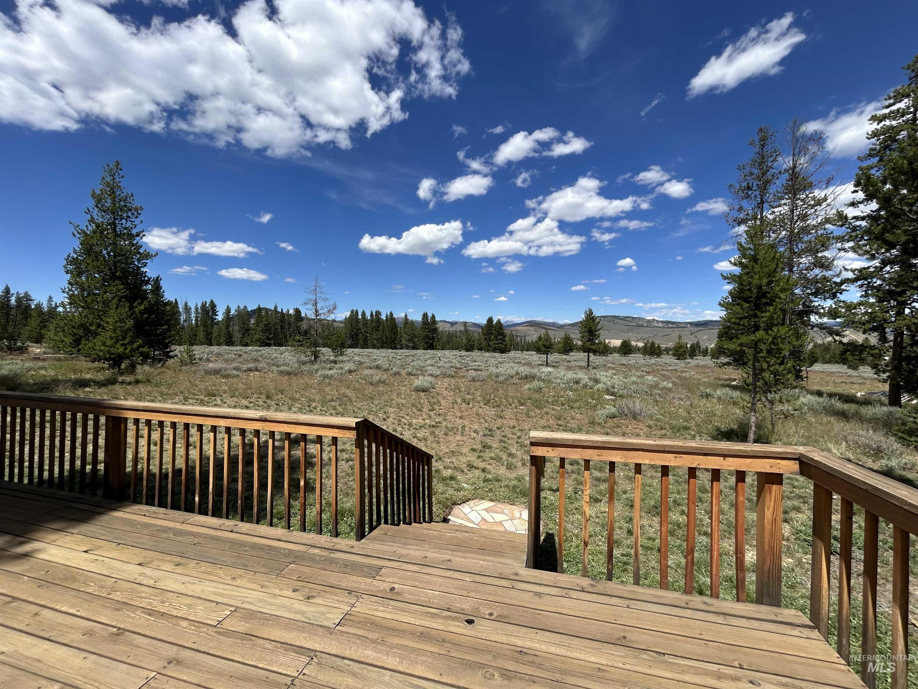 35 Sawtooth Way Stanley, ID 83278 - Photo 10 of 36 Expansive outdoor deck with natural wood finish, featuring a full railing and steps descending to a stone path
