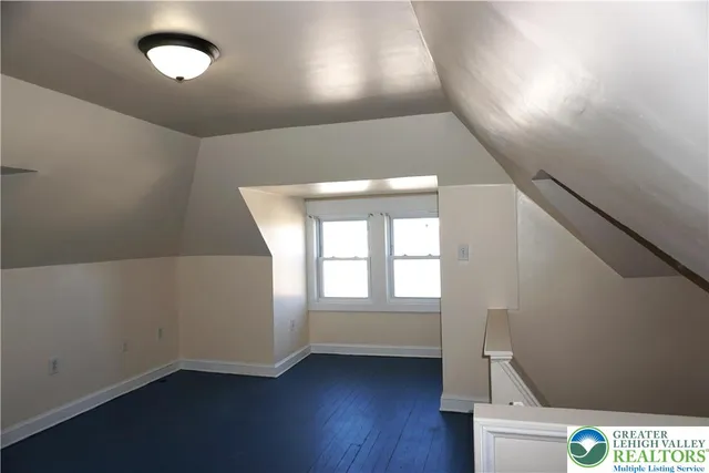 a view of an empty room with wooden floor and fan
