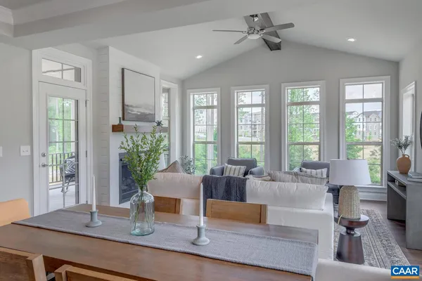 a living room with furniture large windows and wooden floor