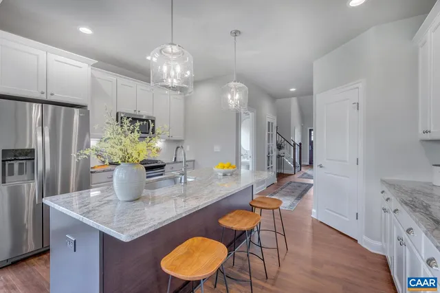 a kitchen with stainless steel appliances granite countertop a table chairs and a refrigerator