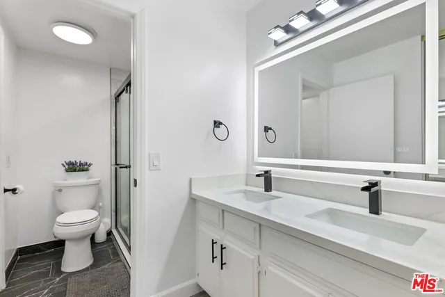 a bathroom with a sink a toilet a mirror and shower