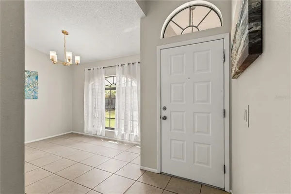 an empty room with chandelier fan and windows
