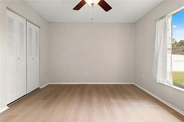 an empty room with a window and a ceiling fan