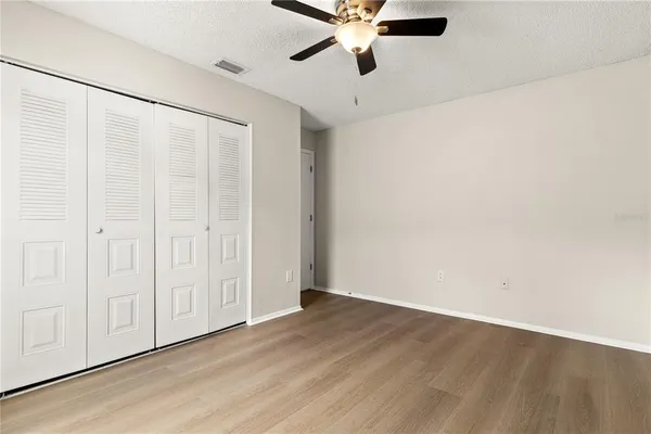 an empty room with wooden floor closet and windows