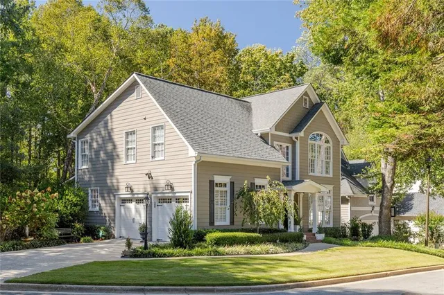 a view of a white house with a yard plants and large trees