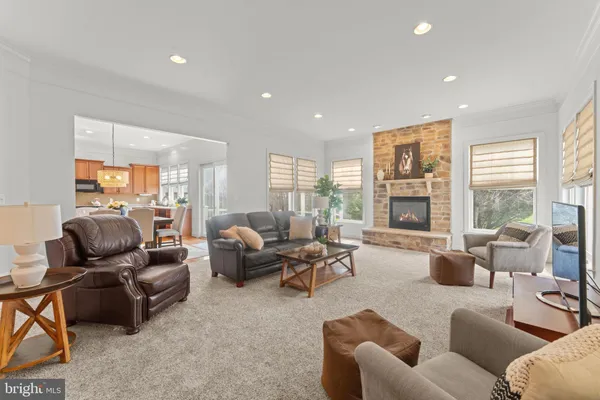a view of a dining room and livingroom with furniture wooden floor a rug a fireplace and a chandelier