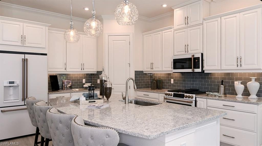 12701 Bellissimo Fort Myers, FL 33913 - Photo 4 of 34 a kitchen with stainless steel appliances kitchen island granite countertop a stove a sink a microwave and cabinets