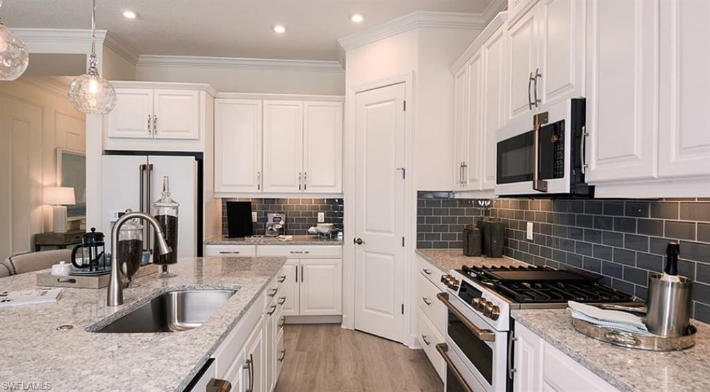 12701 Bellissimo Fort Myers, FL 33913 - Photo 8 of 34 a kitchen with granite countertop a stove a sink and a microwave