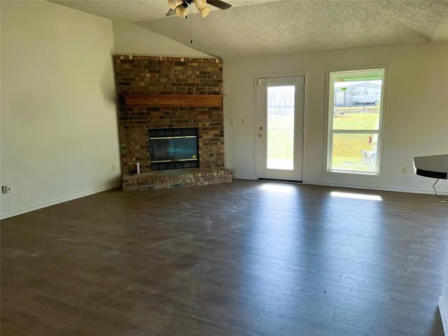 an empty room with wooden floor fireplace and windows