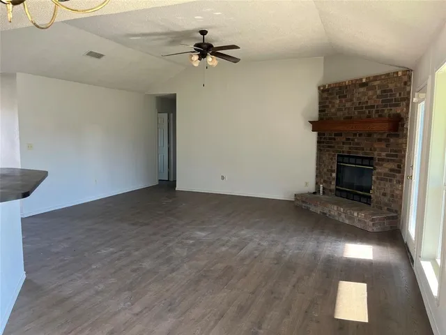 a view of empty room with a fireplace and wooden floor
