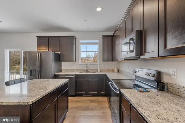 a kitchen with granite countertop a stove a sink and a microwave
