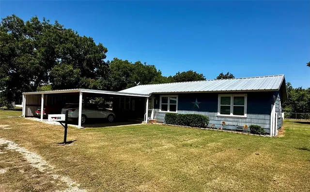 a front view of house with yard and trees in the background