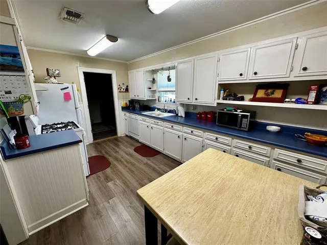 a kitchen with stainless steel appliances granite countertop a sink dishwasher and a refrigerator with wooden floor