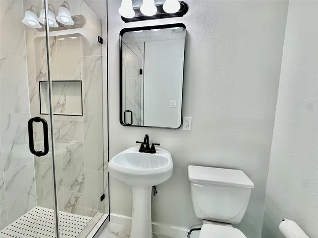 a bathroom with a toilet sink shower and mirror