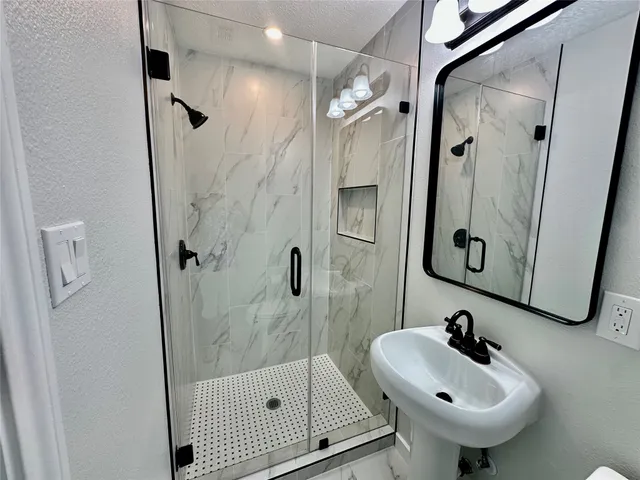 a bathroom with a sink mirror and shower