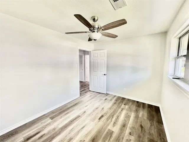 an empty room with windows and fan