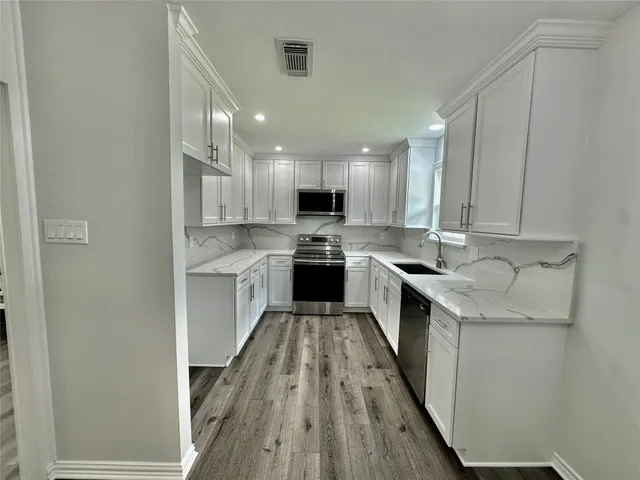 a kitchen with a sink a counter top space stainless steel appliances and cabinets