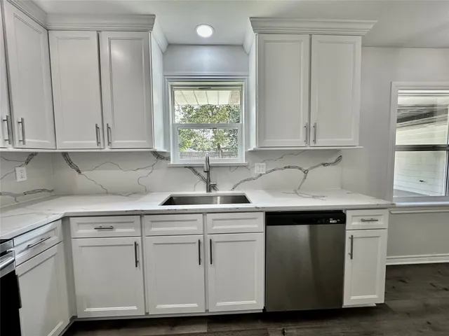 a kitchen with white cabinets and sink