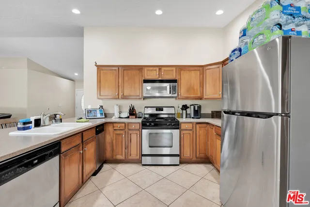 a kitchen with granite countertop a refrigerator sink stove and microwave