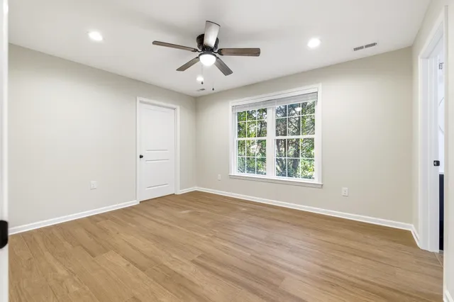an empty room with wooden floor and ceiling fan