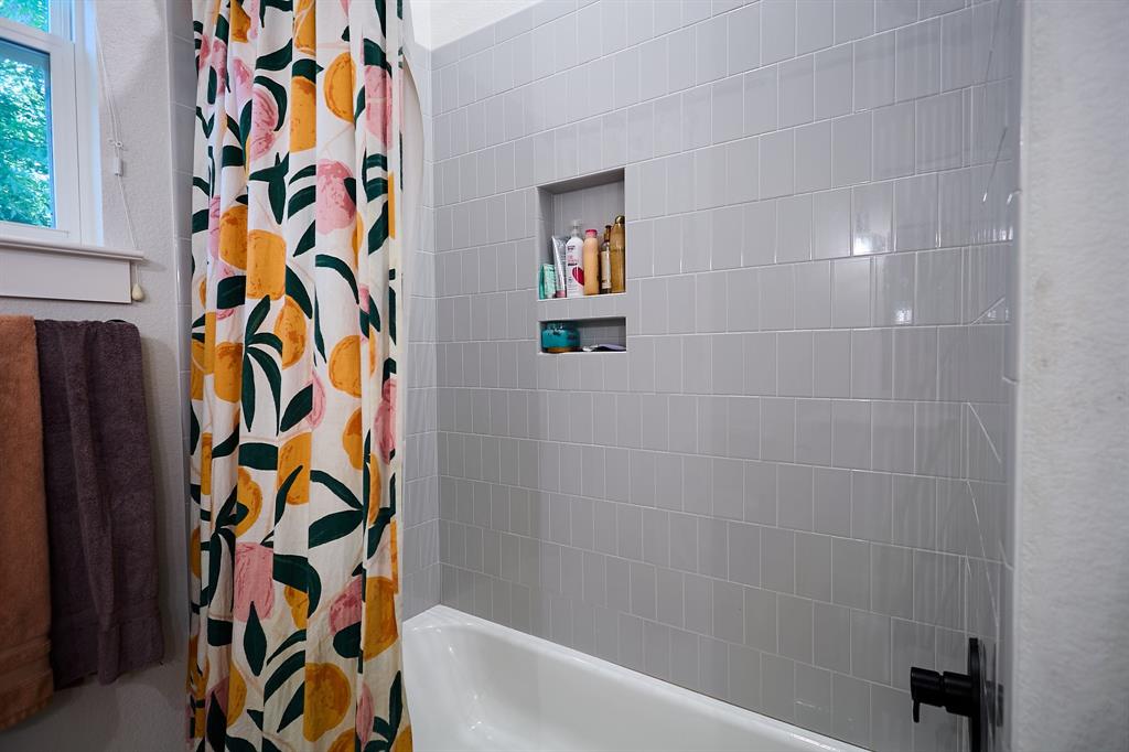 358 Glade Valley Road Azle, TX 76020 - Photo 22 of 35 Bathtub with light gray subway tile surround, integrated shower niche, and matte black plumbing fixtures