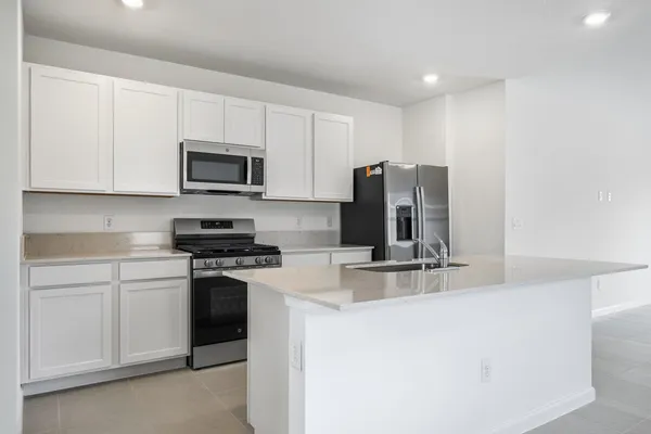 a kitchen with stainless steel appliances granite countertop a stove a sink and a microwave